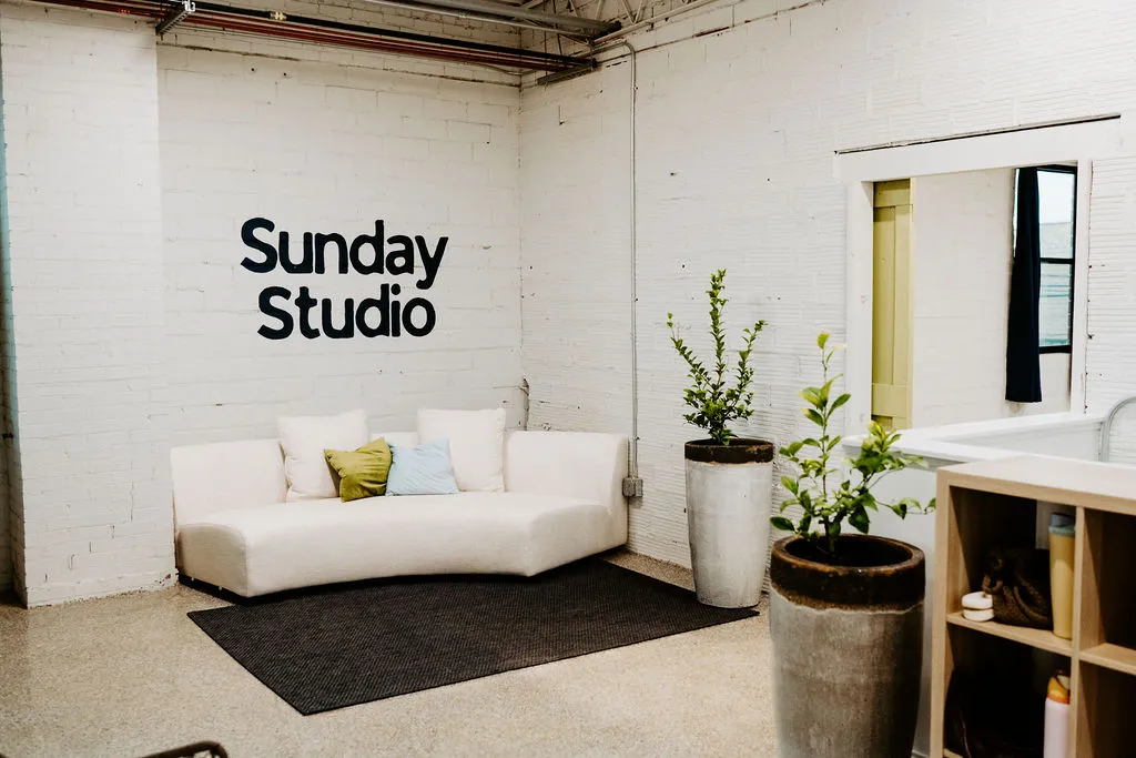 The Sunday Studio lounge with a white sofa, plants and the studio sign